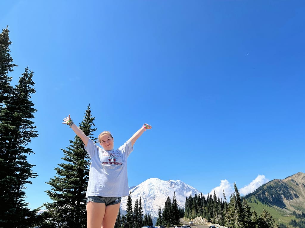 My daughter throwing her arms in the air with Mount Rainier in the distance
