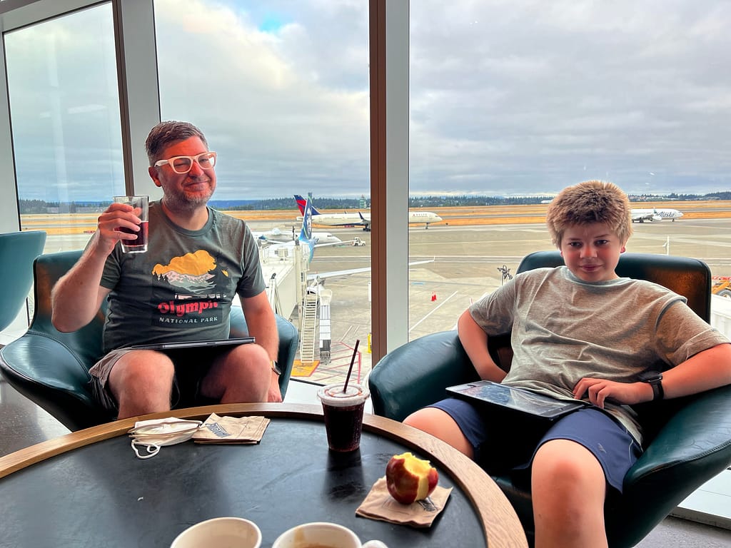 Me with a pint of cider and my son enjoying Alaska Air lounge
