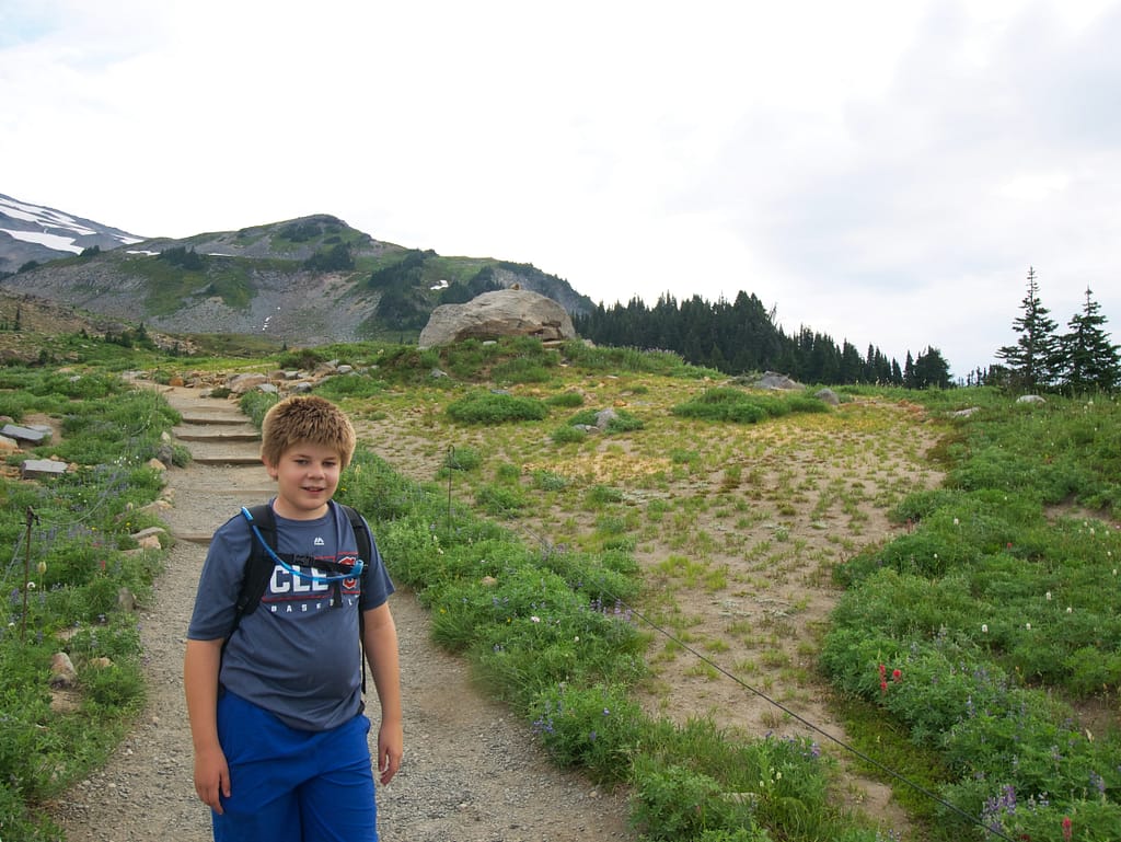 My son with a Rainier marmot on a rock just behind him