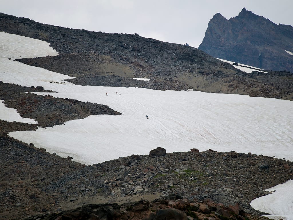 A patch of snow on Mount Rainier with people walking and snowboarding